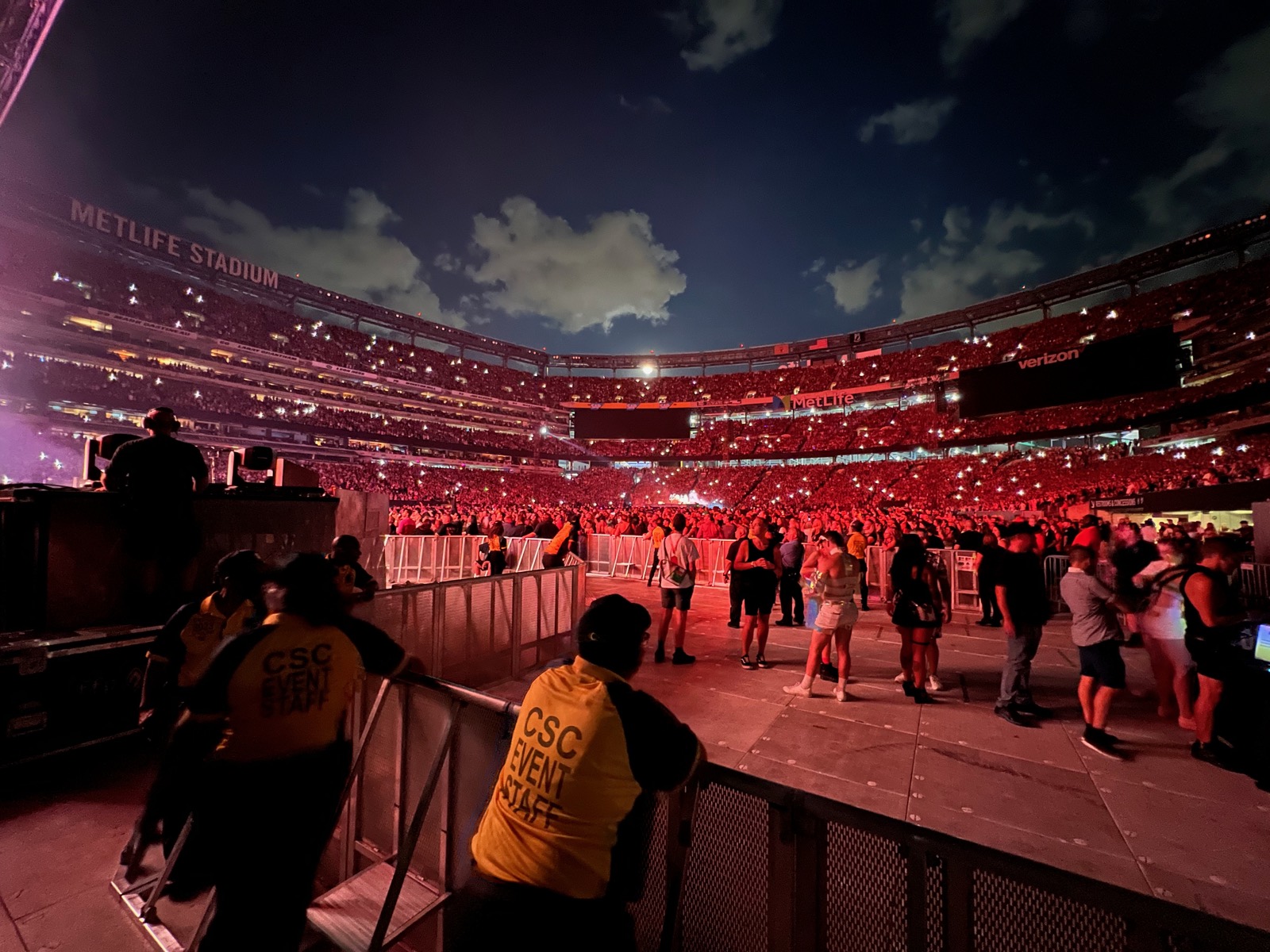 Packed stadium bathed in red light with event crew at the barrier