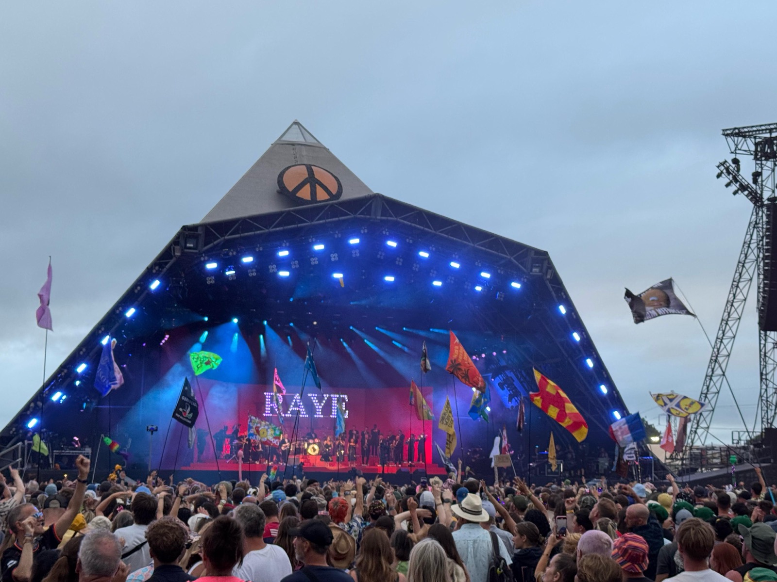 Glastonbury Pyramid Stage lit up at dusk with a packed festival crowd